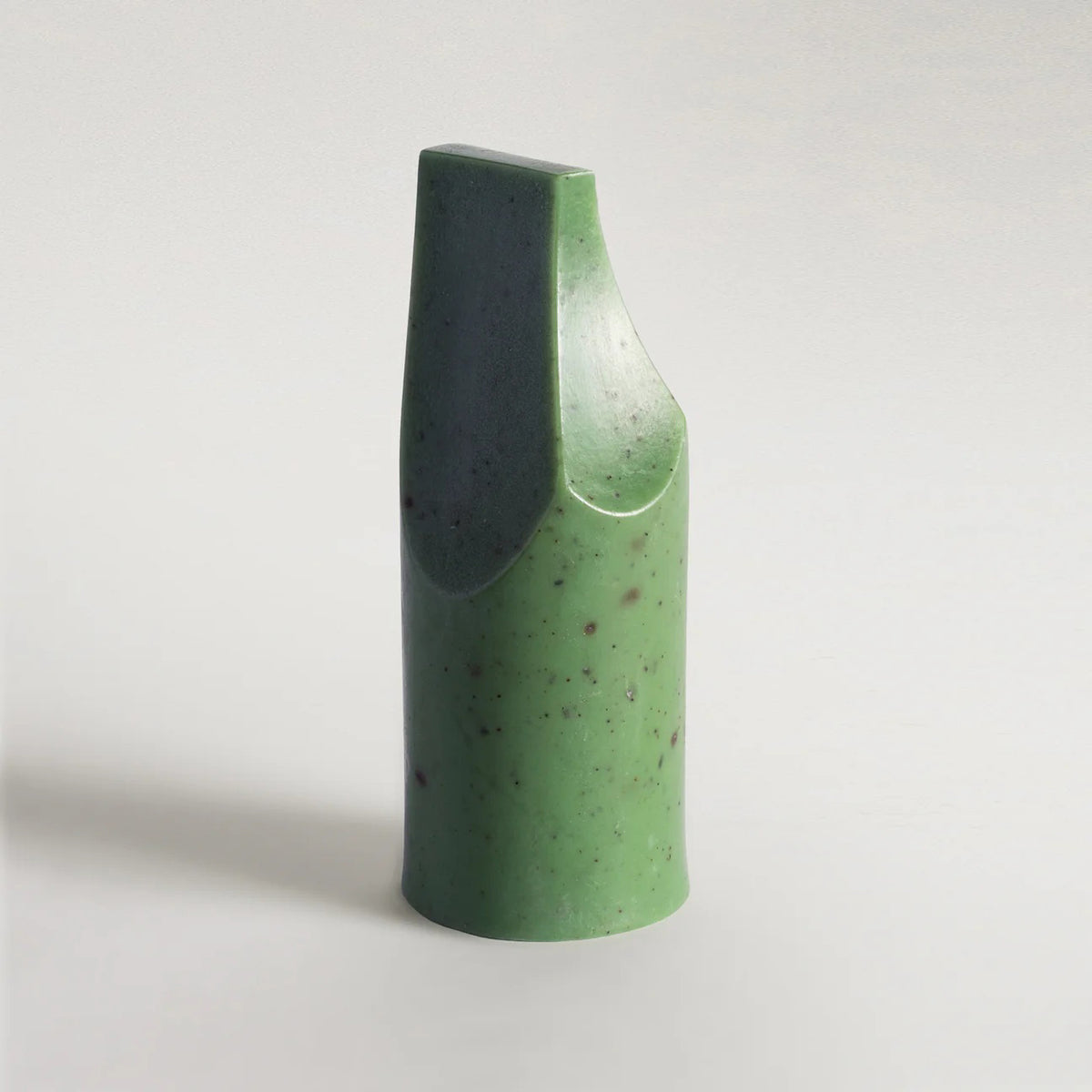 The UME - HERBES DE PROVENCE ERODE MINI SOAP by UME STUDIO is a green, smooth, abstract soap with a tall cylindrical base, slanted flat top, and curved cut on one side, shown against a light gray background.