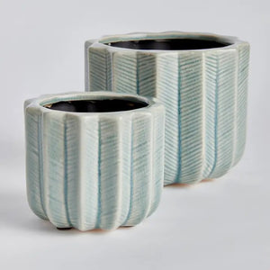 The NAPA HOME AND GARDEN - VELA POT, SMALL is a light blue ceramic decorative flower pot featuring vertical ridges and a cactus-inspired design, shown in a side view with part of another planter visible in the background.