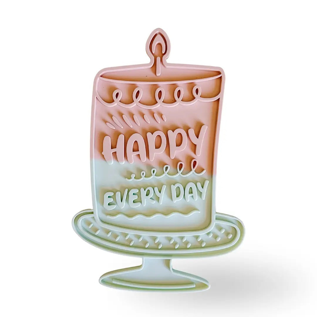 Introducing the HAPPY LICK MAT - PINK by BARKS & BROWNIES: a pastel cake-shaped slow feeder for dogs, labeled “Happy Every Day.” Crafted from BPA-free silicone, it features deep maze ridges for anxiety relief, a non-slip suction base, and is dishwasher safe for easy cleaning.