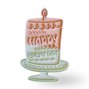 Introducing the HAPPY LICK MAT - PINK by BARKS & BROWNIES: a pastel cake-shaped slow feeder for dogs, labeled “Happy Every Day.” Crafted from BPA-free silicone, it features deep maze ridges for anxiety relief, a non-slip suction base, and is dishwasher safe for easy cleaning.