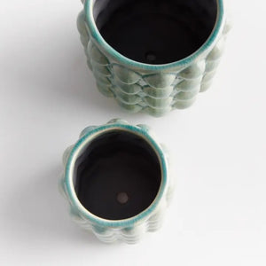 The NAPA HOME AND GARDEN - VALENCIA POT, SMALL by NAPA HOME AND GARDEN is a light green contemporary planter with a glossy seafoam glaze and a textured surface featuring raised circular bumps arranged in a grid pattern.