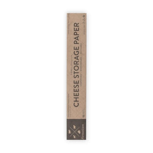 A hand holds a sheet of FORMATICUM - ZERO CHEESE STORAGE PAPER with green illustrations, next to a brown FORMATICUM box. The partially unrolled cheese storage paper is ideal for keeping cheese fresh at home.