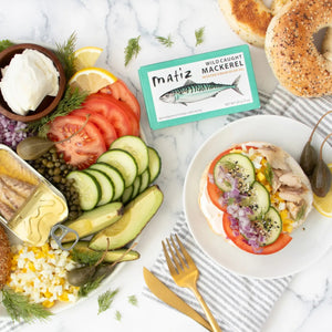 A teal tin of MATIZ ESPANA - Wild Caught Mackerel in Extra Virgin Olive Oil, made in Spain and featuring a mackerel illustration along with text highlighting 380 milligrams of Omega-3 per serving. Net weight: 85g (3oz).