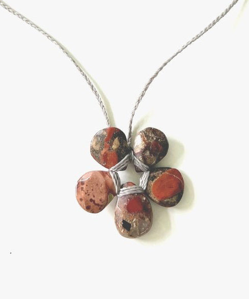 The ANN LIGHTFOOT - PETITE RED SPOTTED CHALCEDONY FLOWER NECKLACE showcases five marbled stones in warm browns and reds, resembling faceted spotted red chalcedony, elegantly held by silver wire and suspended from an adjustable braided nylon tie.