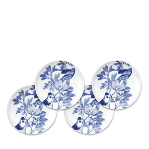 Three CASKATA ARBOR BLUE BIRDS PLATES, featuring blue and white botanical and bird motifs on premium porcelain, are stacked on a table beside a silver spoon and a folded blue napkin.