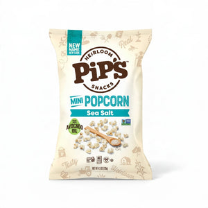 A bag of PIPCORN - SEA SALT POPCORN shown next to a smaller, older version of the PIP’S HEIRLOOM SNACKS packaging.