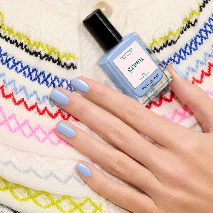 A white nail polish brush spreads MANUCURIST - GREEN™ NAIL POLISH IN LILAS by MANUCURIST INC, a pale lavender vegan formula, smoothly across the surface to create a glossy, even layer.