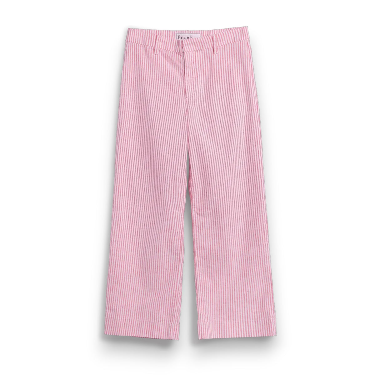 A barefoot person stands on sandy ground near green bushes, wearing FRANK &amp; EILEEN's Wexford Wide Leg Linen Pant in Red Stripe and a white t-shirt, photographed from behind on a sunny day.