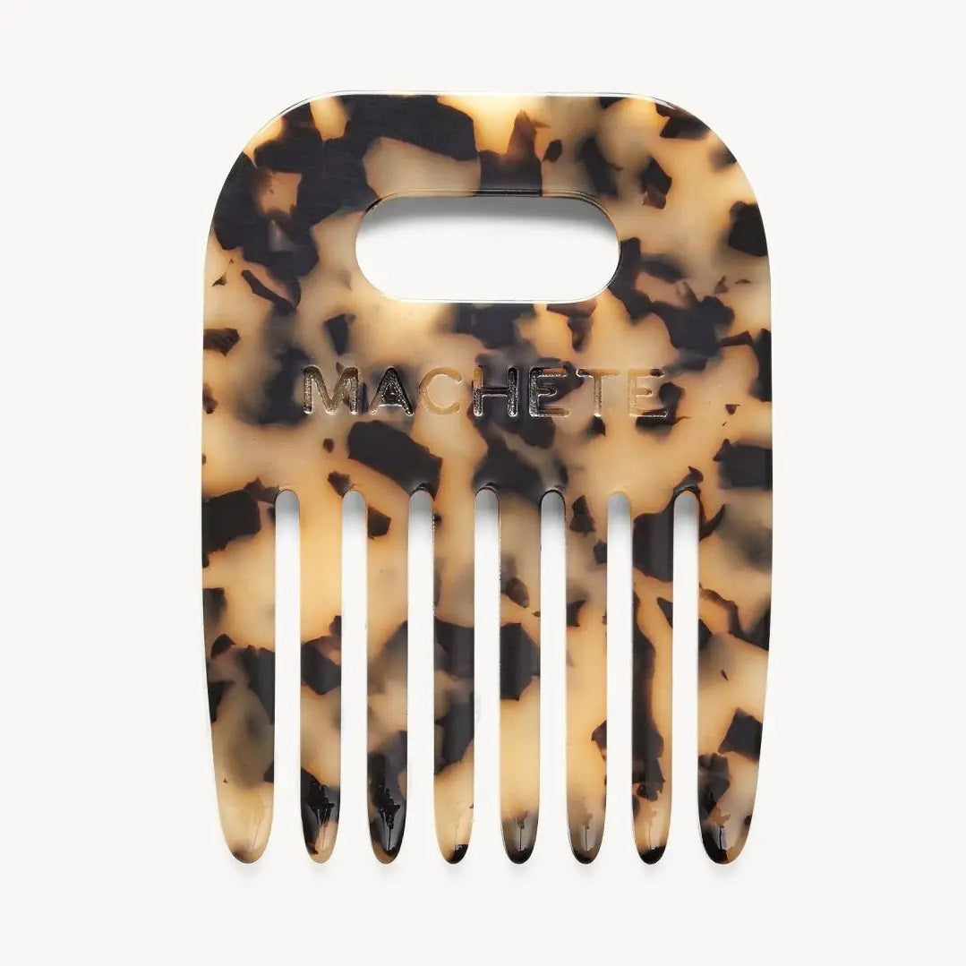 The MACHETE - No. 4 Comb in Blonde Tortoise is a wide-tooth Italian acetate comb with a tortoiseshell pattern, rectangular handle cutout, and "MACHETE" embossed on the front—ideal for detangling curly hair.
