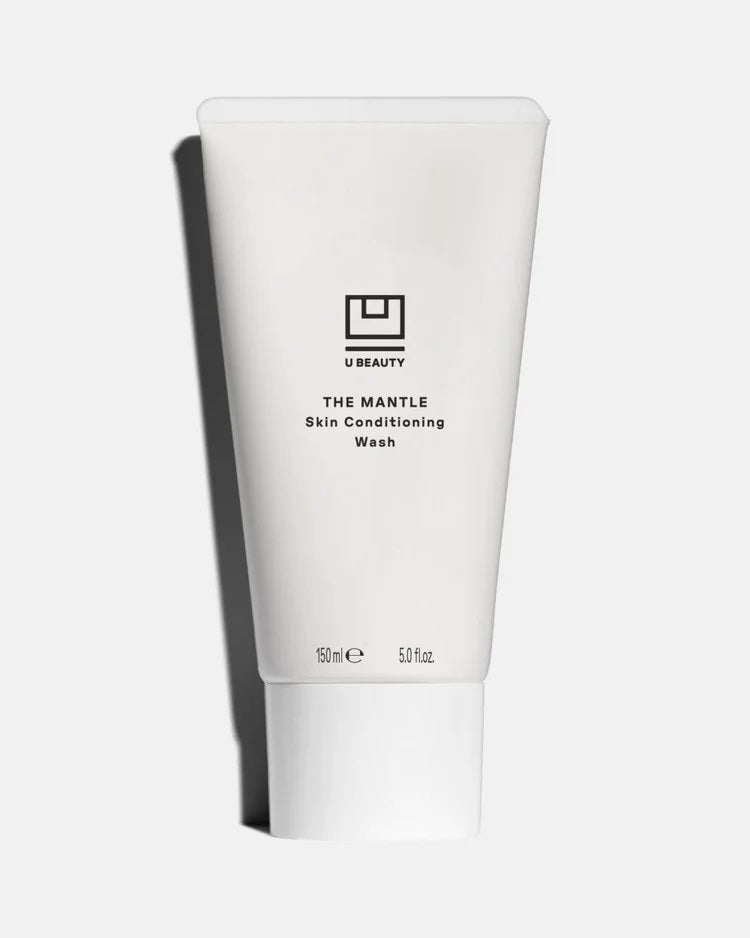 A 150ml tube of U BEAUTY THE MANTLE SKIN CONDITIONING WASH features a minimalist black logo and text on white, displayed against a light background—perfect as the second step in your double cleanse routine.