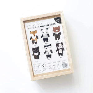 A wooden toy set titled "WEE GALLERY - MIX & MATCH ANIMAL TILES" by WEE GALLERY shown on a white background. The visible toy piece features a cartoonish animal, combining traits of a fox and a bear, painted in brown, white, and black colors. Perfect for creative play and developing motor skills, the toy is presented in a wooden box.