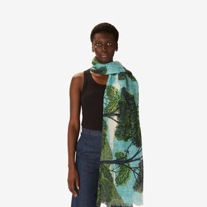 The INOUI EDITIONS - AMBROISE SCARF IN GREEN by INOUI features an illustrated design of green trees and blue sky on a plain white background, evoking a scenic outdoor view reminiscent of nature.