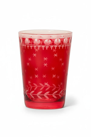 A ZODAX HAND CUT TEA LIGHT CUP, a red borosilicate glass votive holder with etched star and circle patterns, containing a lit candle and sitting on a gold-toned coaster.