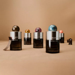 A bottle of MOLTON BROWN - RHUBARB & ROSE EAU DE PARFUM, featuring a matte black body and a round marbled pink cap, displayed against a plain white background.