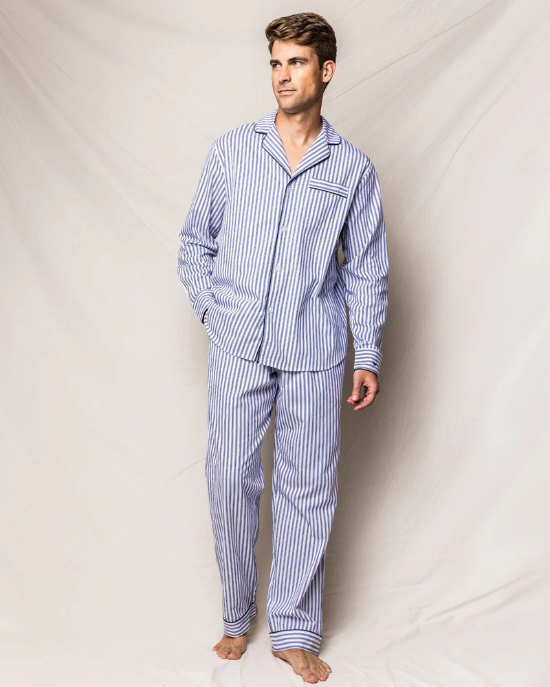 The FEARRINGTON LIFESTYLE COLLECTION - MENS TWILL NAVY FRENCH TICKING PAJAMAS by PETITE PLUME is neatly folded and displayed. This striped pajama set, made from the finest quality cotton, features white and navy blue vertical stripes in a traditional French ticking design with a small embroidered sheep on the chest pocket. It has a collar, buttons, and an attached hang tag with branding.