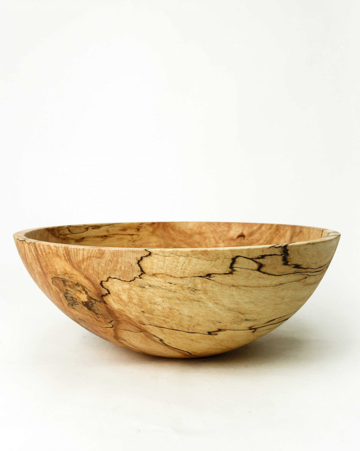 The SPENCER PETERMAN Classic Round Spalted Maple Bowl 18" by PETERMANS BOARDS &amp; BOWLS INC features a handcrafted, smooth, rounded design and unique natural grain patterns, displayed against a plain white background.