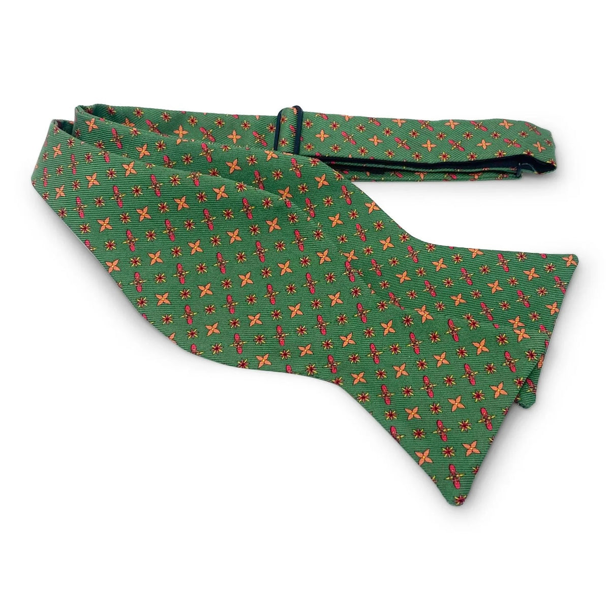 The BIRD DOG BAY PETER-BLAIR Foulard Silk Bow Tie in Green features a repeating red and yellow cross pattern, displayed flat against a white background. This adjustable neck bow tie blends timeless style with modern versatility.