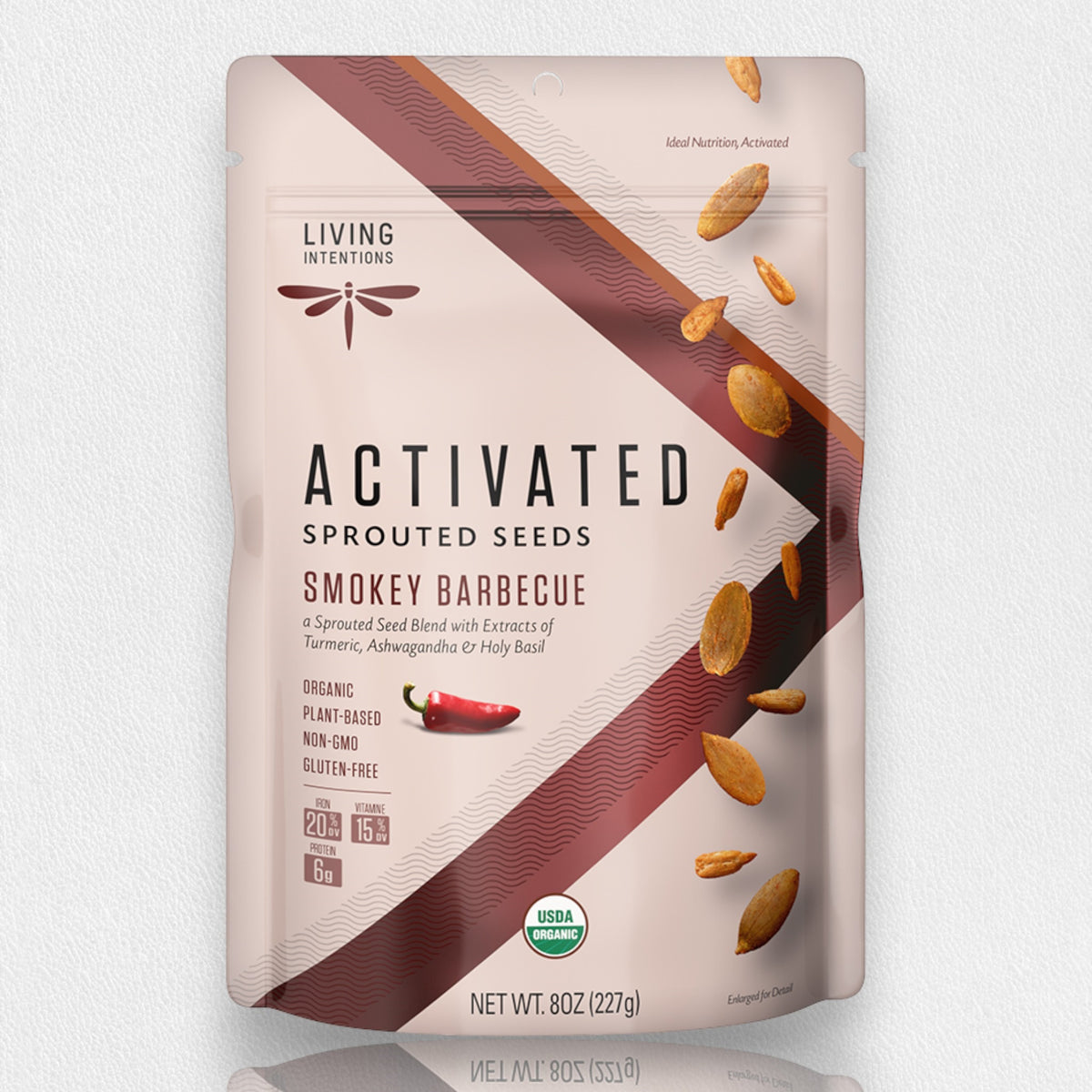 A beige and maroon-packaged 8 oz (227g) bag of LIVING INTENTIONS - SMOKEY BARBEQUE SPROUTED SEEDS. The packaging highlights that it is organic, plant-based, non-GMO, and gluten-free. It features images of seeds and a chili pepper, emphasizing its use of organic ingredients for a tasty superfood blend.
