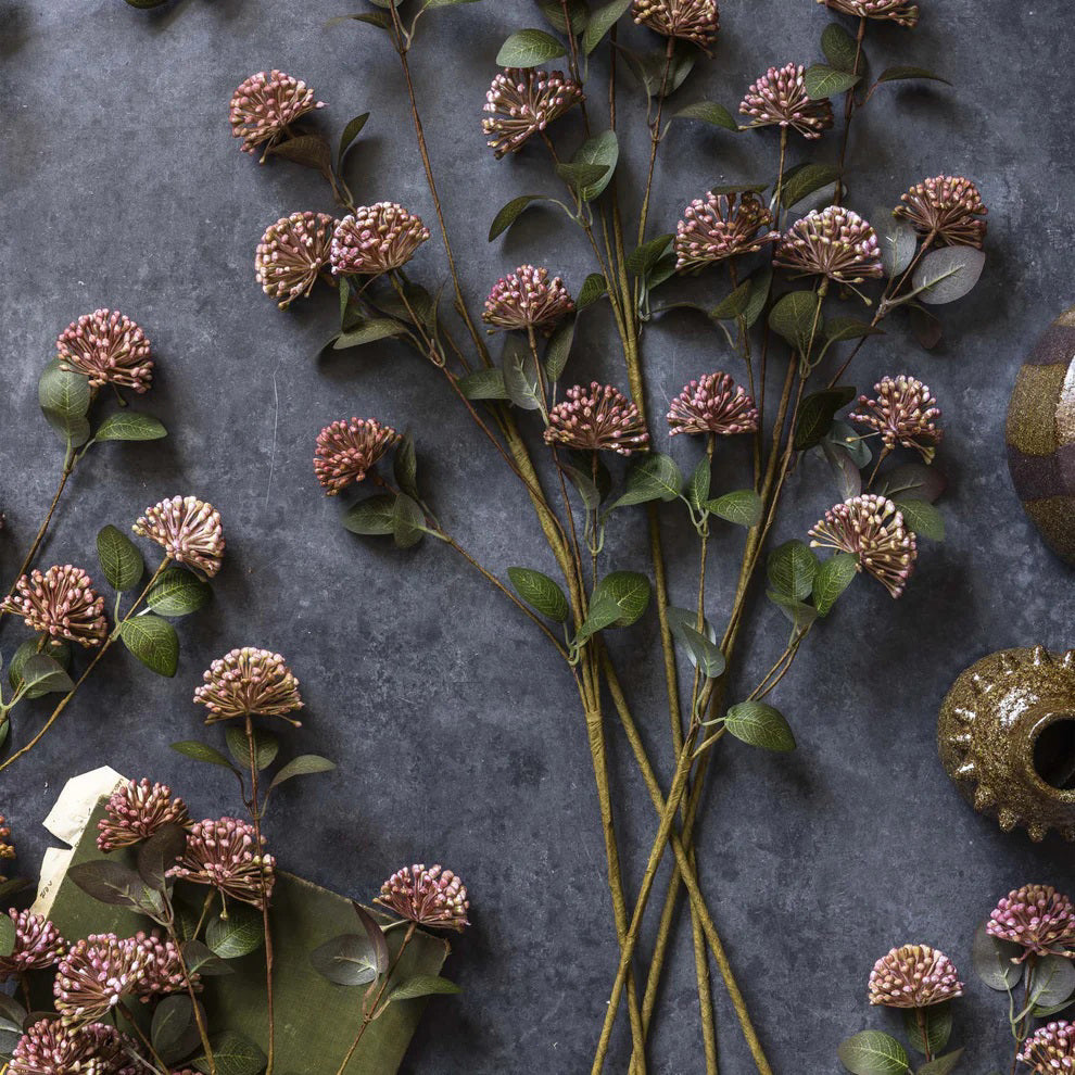 A single artificial flower stem with green leaves and clusters of small pink blossoms, ideal for bouquets or pairing with ABIGAIL AHERN - EUCALYPTUS BERRY from ABIGAIL AHERN.