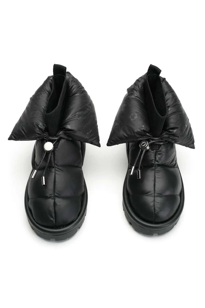 The METALLIC PILLOW BOOT by FLUFIE is a black, high-top winter boot with a padded, quilted design. It features a side zipper and a ridged sole, with the brand name "FLUFIE" embossed on the side of the sole. Insulated with goose down and boasting an anatomic insole, this boot is perfect for cold weather.