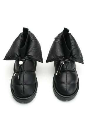 The METALLIC PILLOW BOOT by FLUFIE is a black, high-top winter boot with a padded, quilted design. It features a side zipper and a ridged sole, with the brand name "FLUFIE" embossed on the side of the sole. Insulated with goose down and boasting an anatomic insole, this boot is perfect for cold weather.