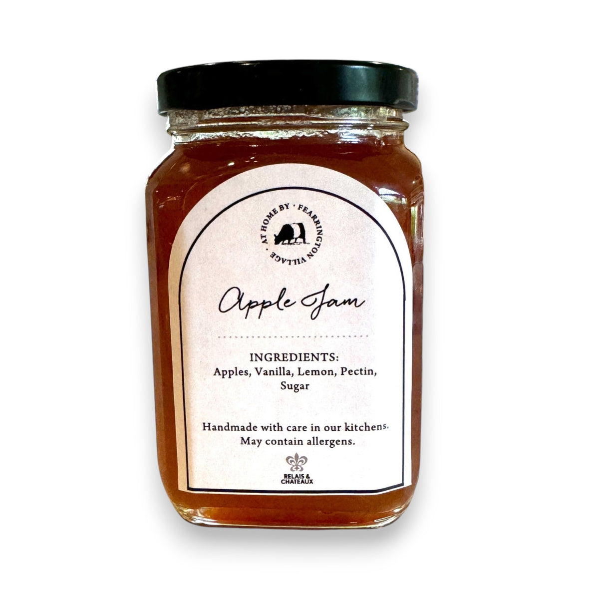 A jar of Fearrington Signature Collection - Apple Jam from Fearrington House is shown. The jar has a black lid and a white label with black text, listing ingredients like apples, sugar, and cinnamon. Perfect for spreading on toast or scones, it features a black and white striped ribbon adorning the lid.