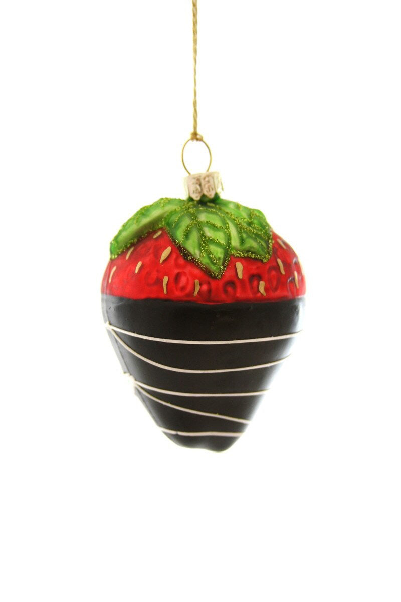 The CHOCOLATE DIPPED STRAWBERRY ORNAMENT by CODY FOSTER features a glass strawberry dipped in chocolate with white stripes and green leaves, hanging by a gold string—an ideal festive treat for dessert lovers.