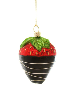 The CHOCOLATE DIPPED STRAWBERRY ORNAMENT by CODY FOSTER features a glass strawberry dipped in chocolate with white stripes and green leaves, hanging by a gold string—an ideal festive treat for dessert lovers.