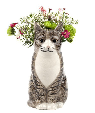 Ideal for cat lovers, the QUAIL DESIGNS QUAIL CERAMICS - MILLIE CAT BUD VASE features a charming tabby cat with brown and black stripes, white chest and paws, and a hollow back to display your favorite flowers.