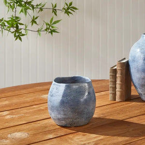 The NAPA HOME AND GARDEN - CASPIAN CACHEPOT is a round, blue ceramic vase with a glossy, mottled finish and speckled pattern—ideal for decorative use on any shelf or table.
