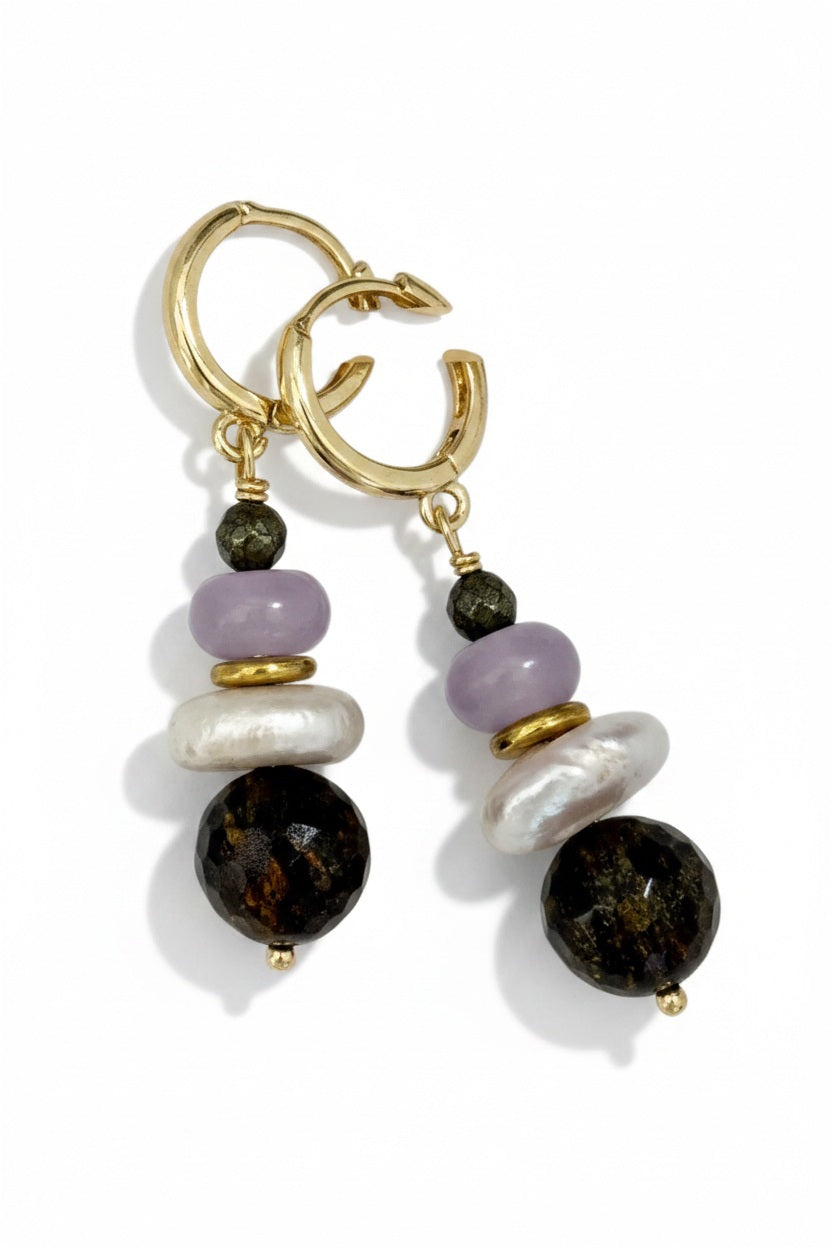 The SANDRINE FRANCE STUDIO JOY EARRINGS from SANDRINE FRANCE STUDIO feature gold hoops adorned with dangling black, white, purple, and gold beads, layered together for a striking and unique statement piece.