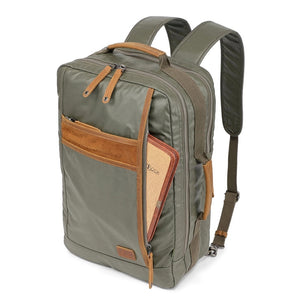 The TSD BRAND Madrone Coated Canvas Backpack in army green features brown leather accents, zippers, a top flap, side handles, metal rings, and a leather logo patch; shown lying flat to display these details.