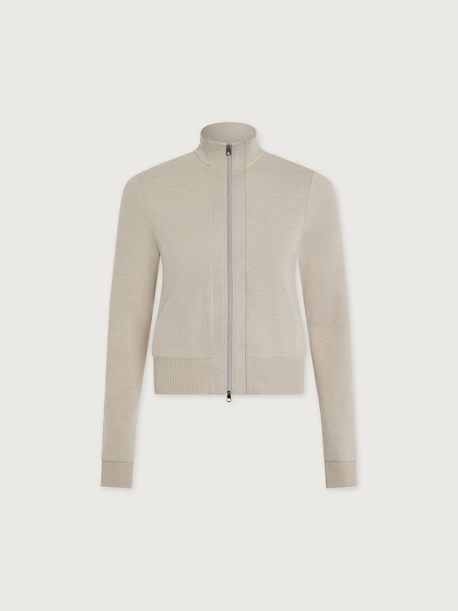 A person wears a light beige Varley Rufus Cropped Zip Through Sweat in Pebble Marl with a high collar and matching pants.