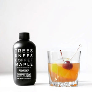 A black bottle labeled “TREES KNEES COFFEE MAPLE” features white text and displays both the Bushwick Kitchen and Stumptown Coffee Roasters logos. With a black cap and 11.5 oz (326g) of gluten-free maple syrup infused with rich coffee flavor, BUSHWICK KITCHEN - ‘TREES KNEES’ COFFEE MAPLE SYRUP makes an excellent addition to any maple syrup gift set.
