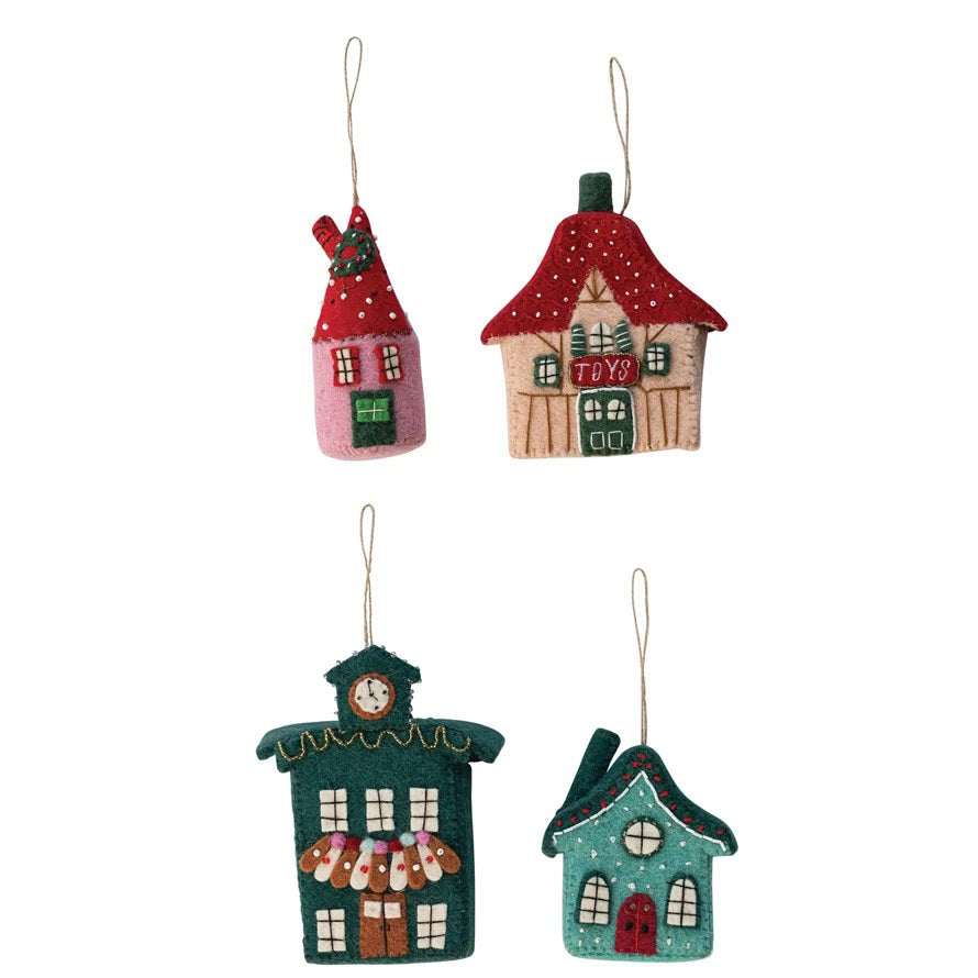 The CREATIVE COOP HANDMADE FELT VILLAGE BUILDING ORNAMENT set includes four wool felt ornaments with stitched, beaded details and hanging loops: a red house, toy shop, clock tower, and festive teal house.