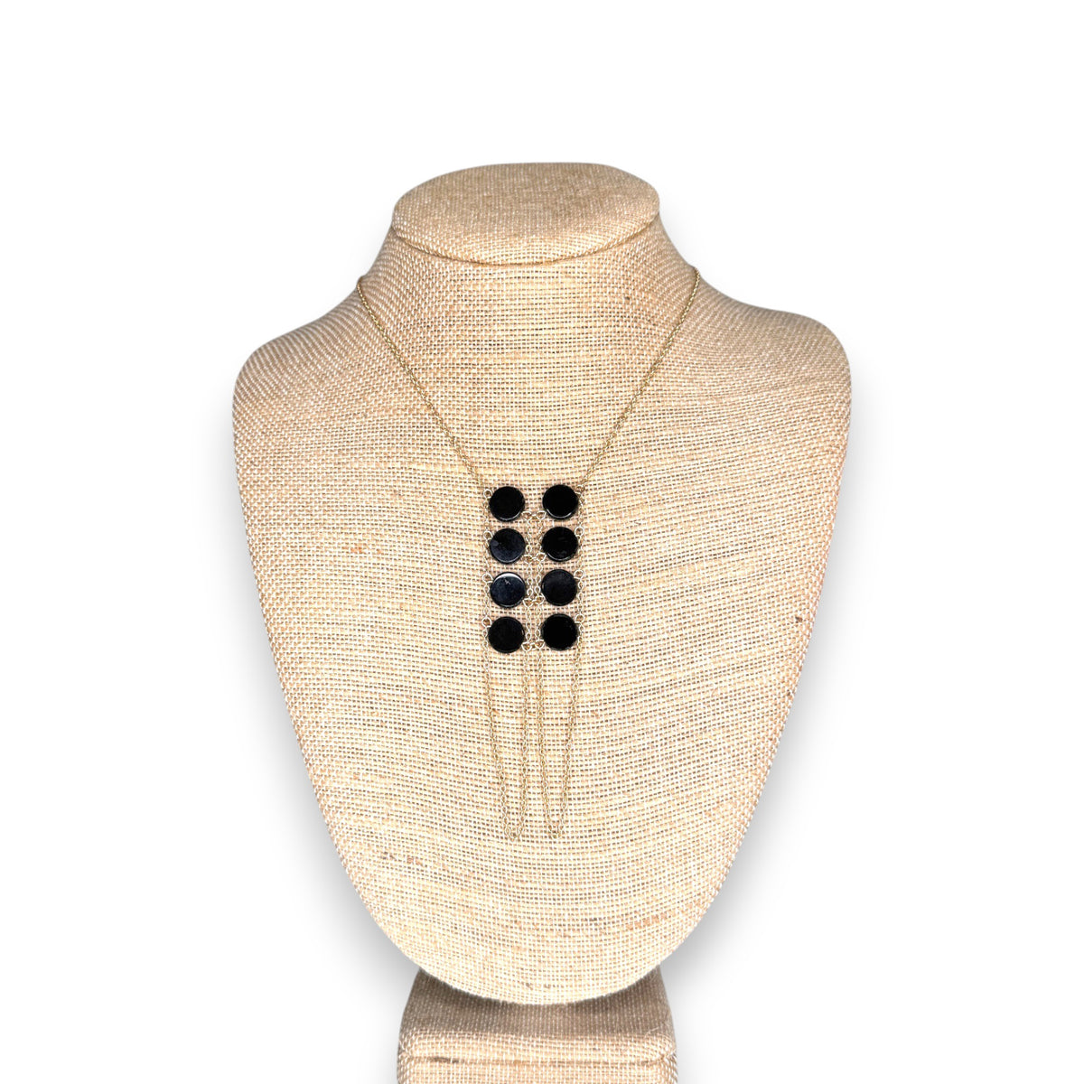 The GOLDISH DOUBLE LADDERS TO BLISS BLACK ONYX CIRCLE STONE NECKLACE, featuring three vertical rows of black onyx stones, is shown on a beige fabric bust stand against a white background.