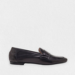A single MICHELE LOPRIORE - PAOLA LOAFER in black is displayed against a plain white background. The shoe features a sleek and minimal design with genuine leather, a low heel, and a classic penny strap across the top, exuding an understated moccasin style by MICHELE LOPRIORE.