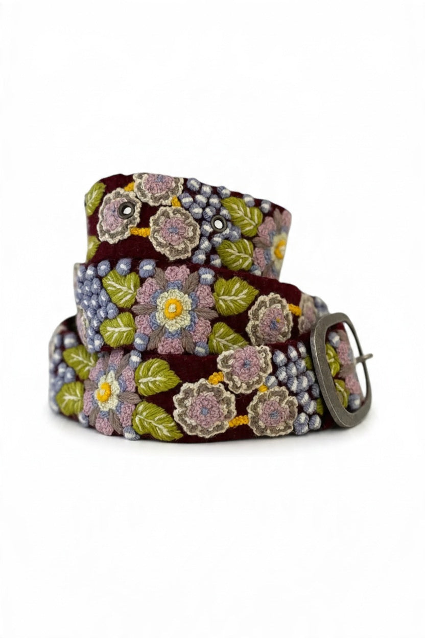 JENNY KRAUSS - MORNING GLORY FLORAL EMBROIDERED BELT, a coiled burgundy wool belt with intricate, multi-colored floral embroidery and an oval buckle, handcrafted in Peru.