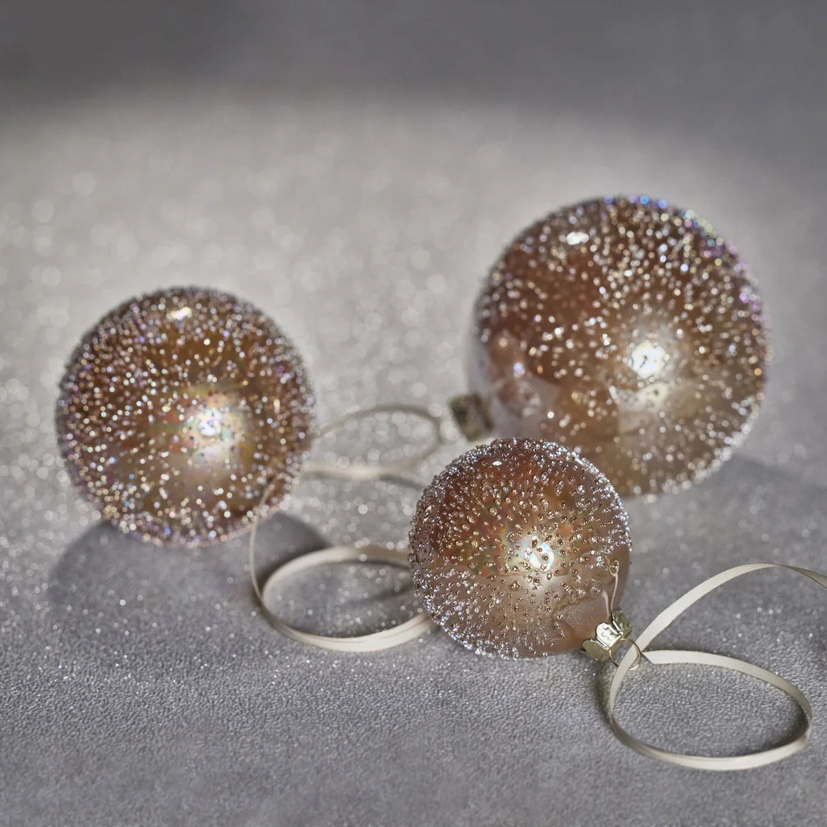A ZODAX GOLDEN SUGAR BEAD GLASS BALL, a 12.07 cm diameter spherical glass Christmas ornament covered in gold-toned beads, hanging from a thin gold ribbon.