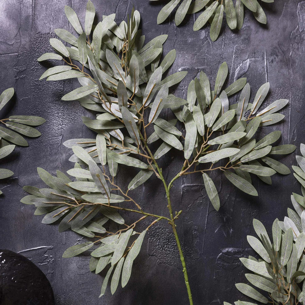 The ABIGAIL AHERN - WILLOW SOFT GREEN features multiple soft green, oval leaves on slender stems, ideal for flower arrangements or mixing with faux foliage, isolated on a white background.
