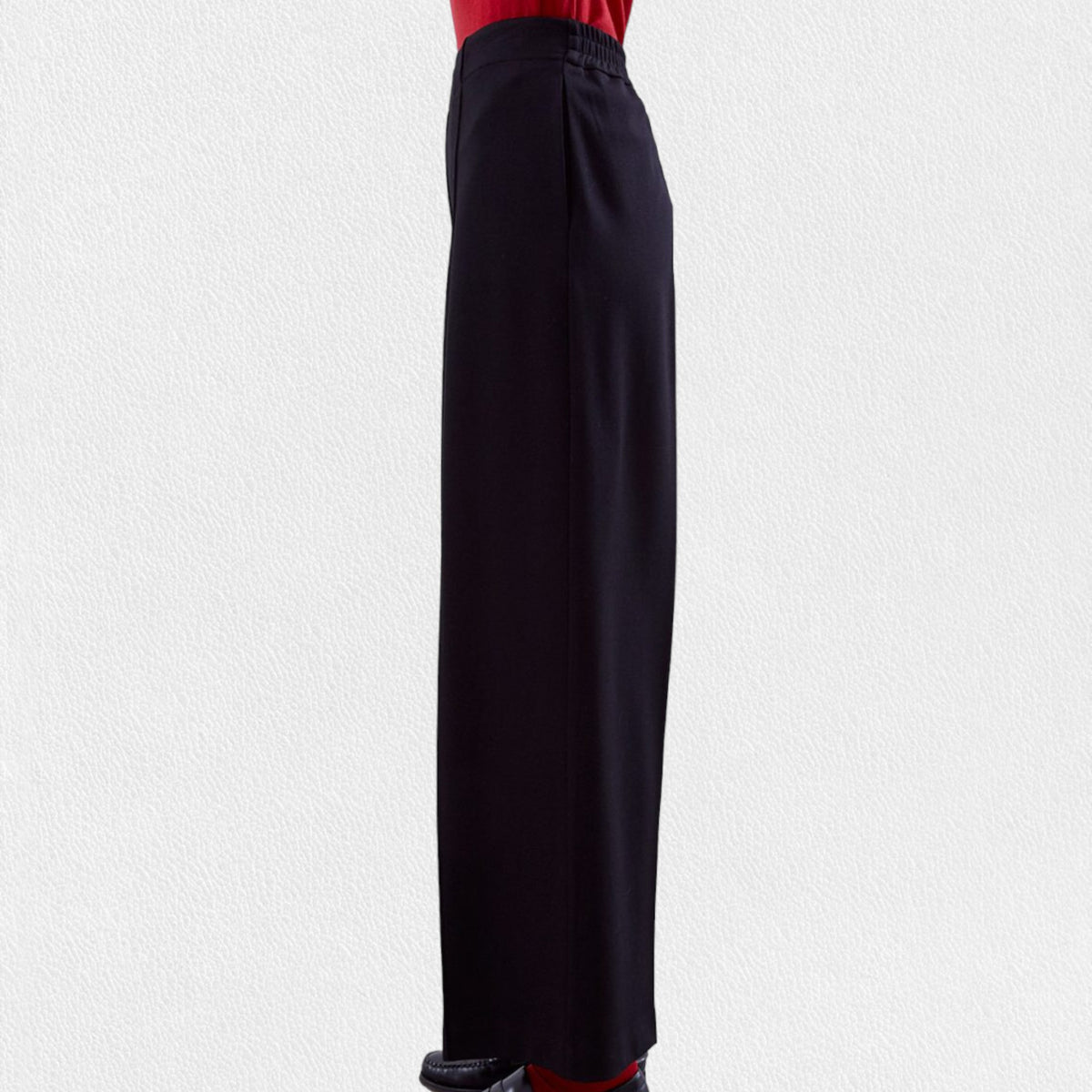 A pair of MEIMEIJ - Pull On Straight Leg Long Pants in black with a red waistband peeking out from the top, worn by a person against a light gray background. These full-length pants from MEIMEIJ feature a clean, minimalist design with no visible pockets or embellishments; they might just become your new favorite.