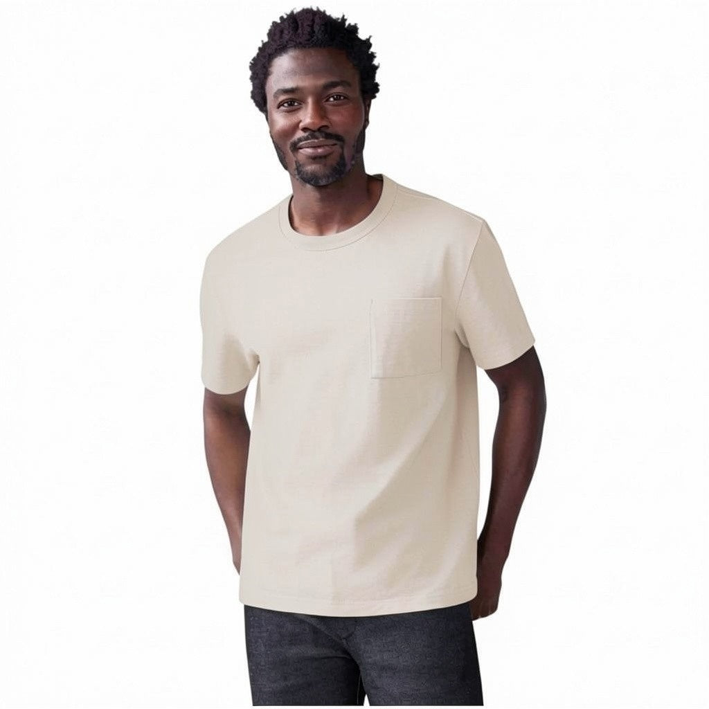 A man with short hair and a beard wears the MACK WELDON Heavyweight Slub Cotton Pocket T-Shirt in Froth, standing against a plain white background with his hands behind his back, looking at the camera.