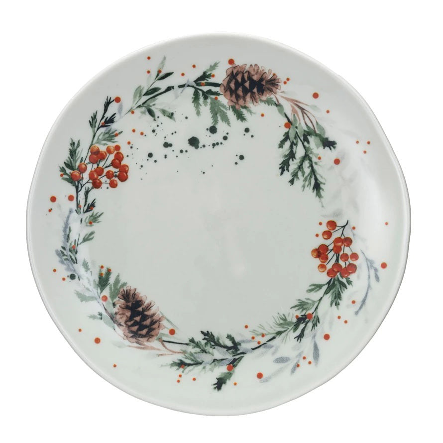 Three CREATIVE COOP STONEWARE PLATES WITH SEASONAL BOTANICALS—a round plate with a gold cheese knife, a triangular plate, and a long oval plate with cookies—display berry and floral designs on a light textured surface.