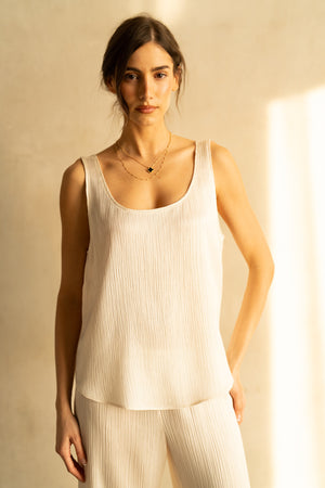 The ROSE & CROWN SATIN RIBBED CAMI is a sleeveless, light beige top with a scoop neckline, shown on a white hanger against a plain background—a versatile wardrobe essential.