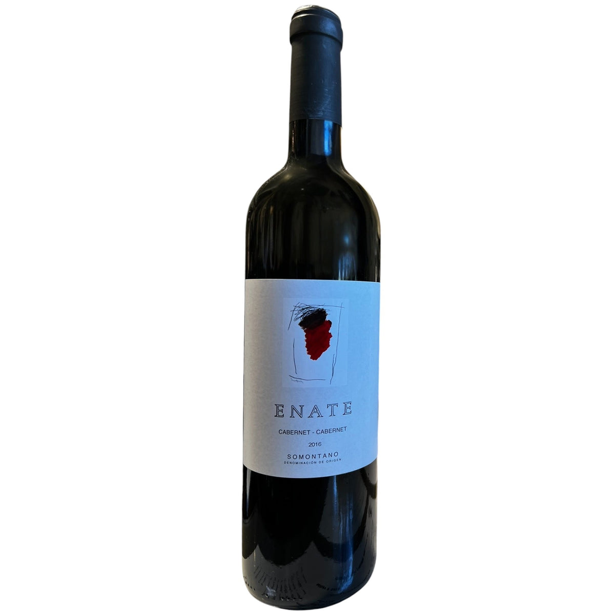 A bottle of ENATE CABERNET SAUVIGNON 2016 by OCEAN SOUTH IMPORTS, a distinguished Somontano wine aged in French oak, stands on a reflective bar counter in a modern restaurant, with menus and a vase of flowers in the background.