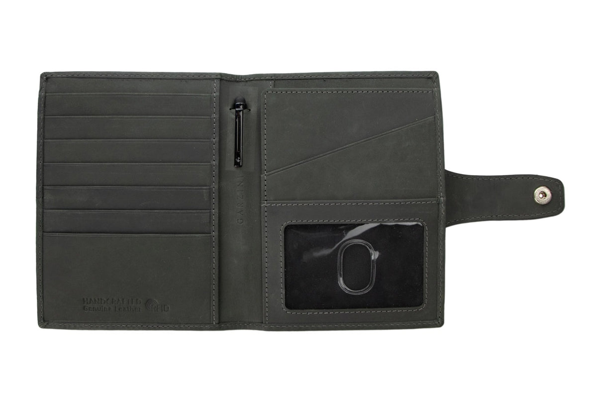 The GARZINI RFID-blocking leather passport holder in black features an AirTag compartment and snap button closure, shown on a white background.