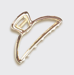 The KITSCH - OPEN SHAPE CLAW CLIP IN GOLD is a minimalist gold metal hair accessory from KITSCH, ideal for styling thick hair and showcased against a plain light background.