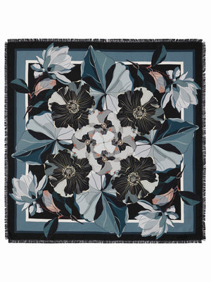 The FRANCO FERRARI - ALOE SILK SCARF 90X90 features a triangular pattern in black, blue, white, and grey with frayed edges. It can be wrapped circularly and tied loosely for a chic look.