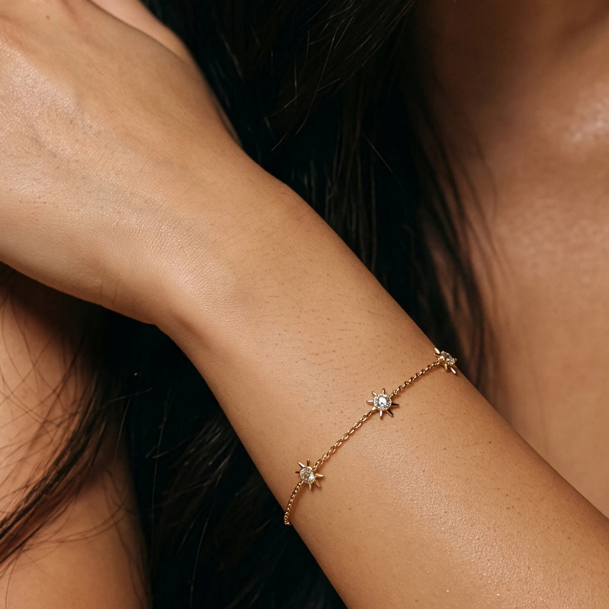The ELLA STEIN - YOU ARE MY SUNSHINE BRACELET by ELLA STEIN is a delicate gold-plated piece featuring three small star-shaped charms on a fine chain with a lobster clasp closure, beautifully displayed on a white background.