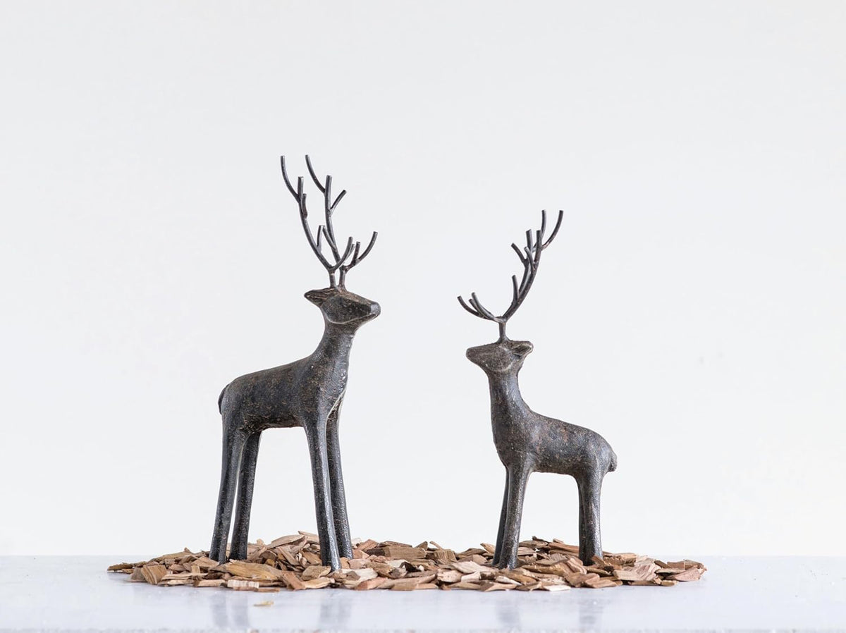 The CREATIVE COOP STANDING CAST IRON DEER features long, narrow legs and tall branching antlers, making it a striking festive decoration that adds elegance to your space. Displayed against a plain white background.